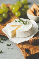 Brie or camembert cheese plate with grapes, crackers and honey