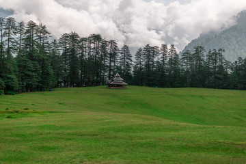 Fototapeta na wymiar A Temple in Green meadows in himalayas, Great Himalayan National Park, Sainj Valley, Himachal Pradesh, India