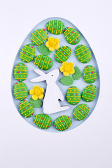 Easter egg frame made of paper, sugar candy eggs, bunny on blue background
