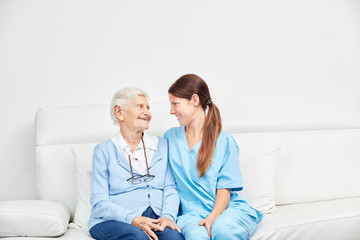 Altenpfleger und Seniorin sitzen auf einer Couch