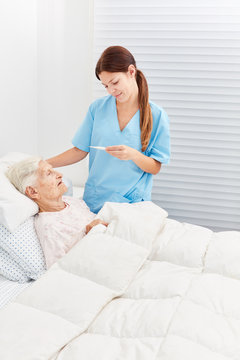 Krankenschwester misst Fieber bei Seniorin