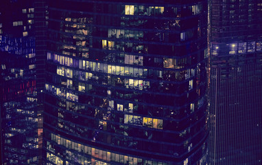 Modern office windows of skyscraper glowing at night. Moscow city. Close up aerial view from rooftop.