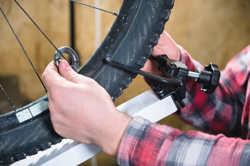 Close-up of men's hands with a specialized wrench on a stand in the workshop tightening the spokes...