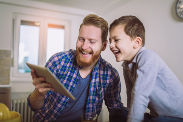 Father And Son Using Digital Tablet At Breakfast Table