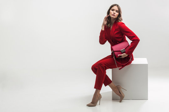elegant woman in red suit holding red hand bag