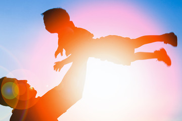 happy parent father with baby silhouette in a park on the nature of the sunset