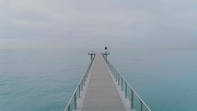Drone camera slowly moves along beautiful simple minimalistic bridge or pier on foggy and cloudy morning. Concept tranquility, peace and calm, perfect location for yoga and mindfulness relaxation