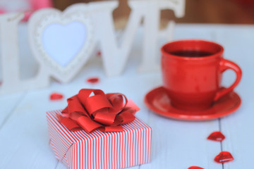 Cup of coffee and gift on blurred background.
