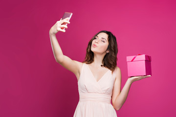 brunette in a dress makes selfie and holds a gift box 