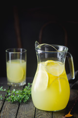 Obraz na płótnie Canvas Iced lemonade with sliced fresh lemons and juice in a jug on dark wooden background.