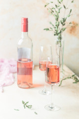 Two glasses and bottle of rose wine on light background.
