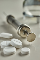 Pills and medical syringe on white background shallow depth of field