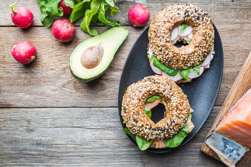 Bagels with cream cheese avocado, fish, arugula and radish. Healthy breakfast food. Top view.