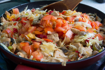 Fry the chicken with mushrooms and vegetables in a pan