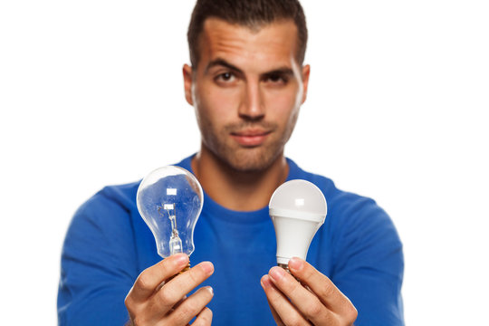 portrait of young man, holding LED bulb and old fachion bulb on white background