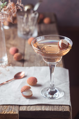 Glass of cold lychee cocktail on the old wooden table, rustic style