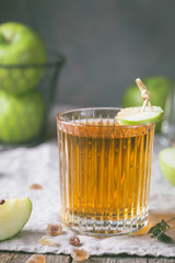 Glass of apple juice with green apples on wooden table, rustic style