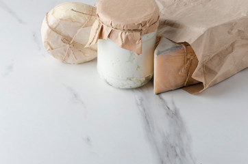 Different kinds of cheese in paper bag on white marble table in the kitchen