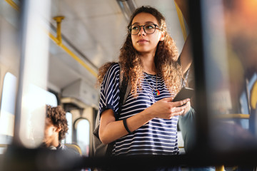 Beautiful mixed race girl with long curly hair using smart phone for reading or writing message...