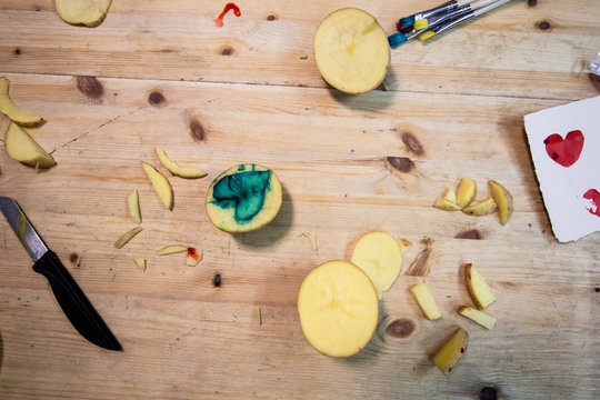 Carving potato. potatoes, colored ink, knives and paper on a wooden table to make stamps with potatoes. educational activity for children where they create a stamp by carving a potato
