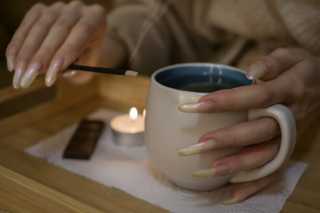 Fototapeta na wymiar Woman hands with long nails holding a cup on tea ceremony
