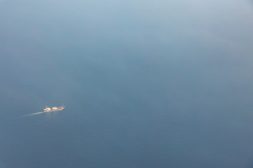 Aerial view of large container ship sails through hazy atmospheric conditions