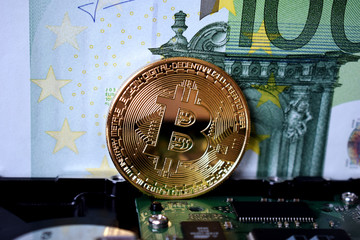  Bitcoin on a computer board and against the background of a 100 euro banknote