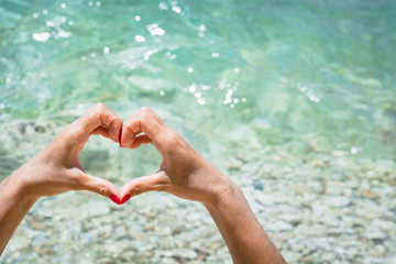 Female hand with red nail in shape of heart. Love concept.