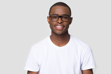 Smiling african american millennial casual man wearing white t-shirt and glasses looking at camera...