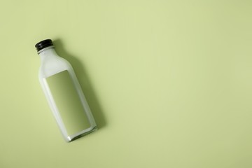 Glass bottle with white liquid (milk, cream, sauce) isolated on colour background