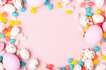 Fototapeta na wymiar Stylish frame made of Easter candy chocolate eggs and Jellybean on pink background