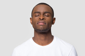 Calm mindful african american man enjoy taking deep breath of fresh air isolated on white studio background, happy black guy with serene face eyes closed meditating feeling harmony and no stress free
