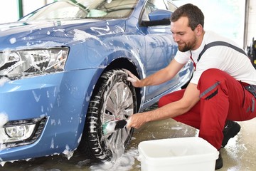customer service in the car trade: worker cleaning a vehicle // Kundendienst in der Autowerkstatt:...