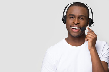 Smiling african american man wearing wireless headset talking to microphone looking at camera...