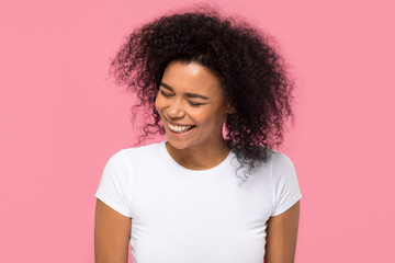 Happy young african american mixed race girl laughing at funny joke isolated on pink blank studio...