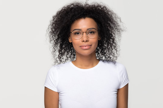 Confident smart attractive young african woman with afro hair wearing glasses looking at camera, millennial black lady isolated on blank grey white studio background, optics concept, portrait