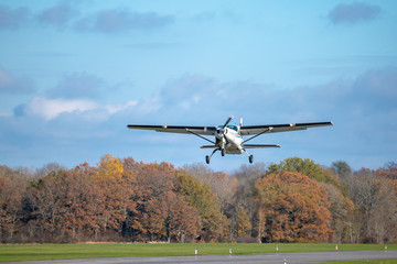 Single prop airplane taking off from the runway in autumn sunlight