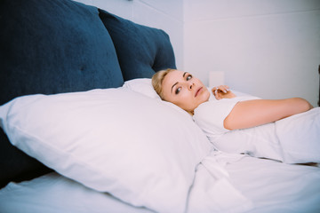 beautiful sad woman lying in bed and looking away