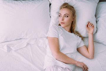 depressed woman in white pajamas lying in bed with copy space