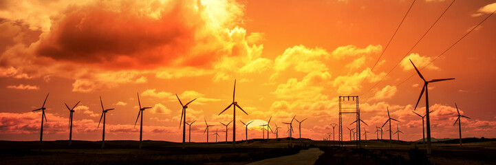 Wind turbine field at sunset, dramatic sky - Powered by Adobe
