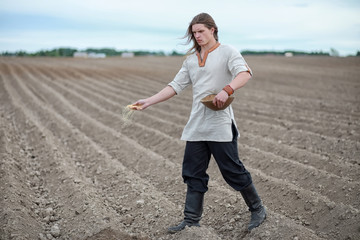 A young peasant sows the field with grain