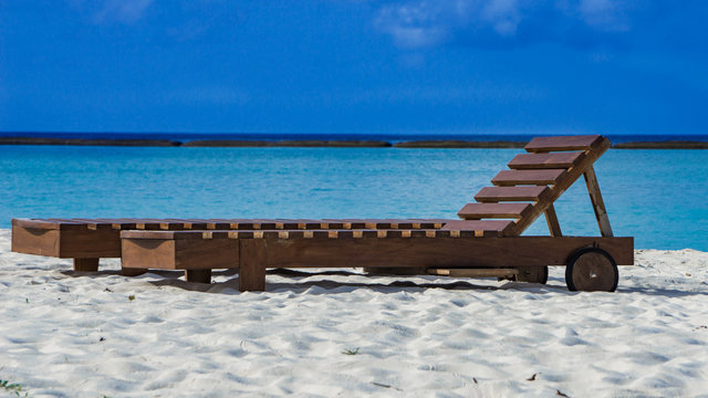 Strandliege aus Holz am Strand auf Insel  Adaaran Select Meedhupparu auf Malediven im Indischen Ozean