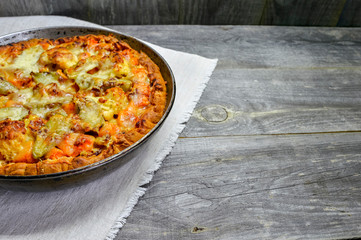 Vegetable and cheese pie in vintage pan on white linen napkin on wooden rustic background