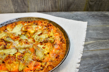 Vegetable and cheese pie in vintage pan on white linen napkin on wooden rustic background