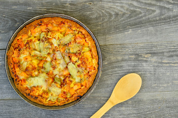 Vegetable and cheese pie in vintage pan with wooden spoon on grey wooden rustic background.