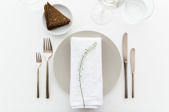 A dinner table with bread and cream cheese for starter, white wine and water to drink.