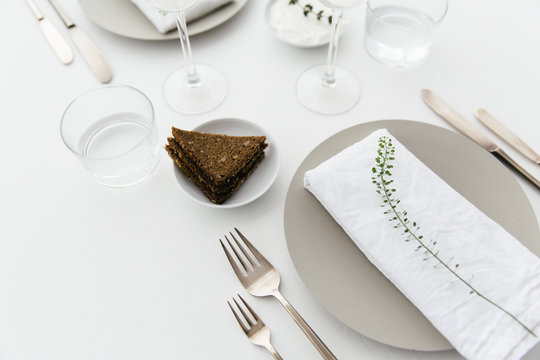 A dinner table for two with bread and cream cheese for starter, white wine and water to drink.