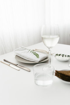 A dinner table with bread and cream cheese for starter, white wine and water to drink.