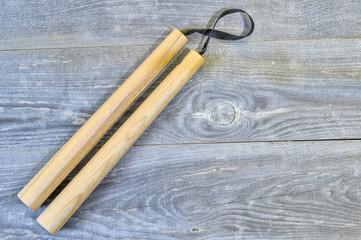 Nunchucks on vintage wooden background. The concept of invitation to training.