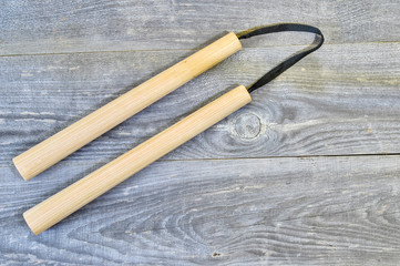 Nunchucks on vintage wooden background. The concept of invitation to training.